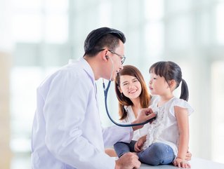 Asian doctor examining a girl by stethoscope