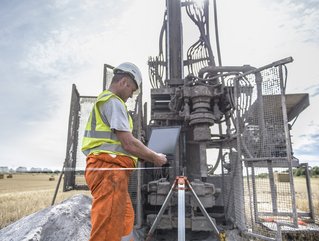 Worker Using Laptop To Survey Drilled Hole Made By Drilling Rig In Field High